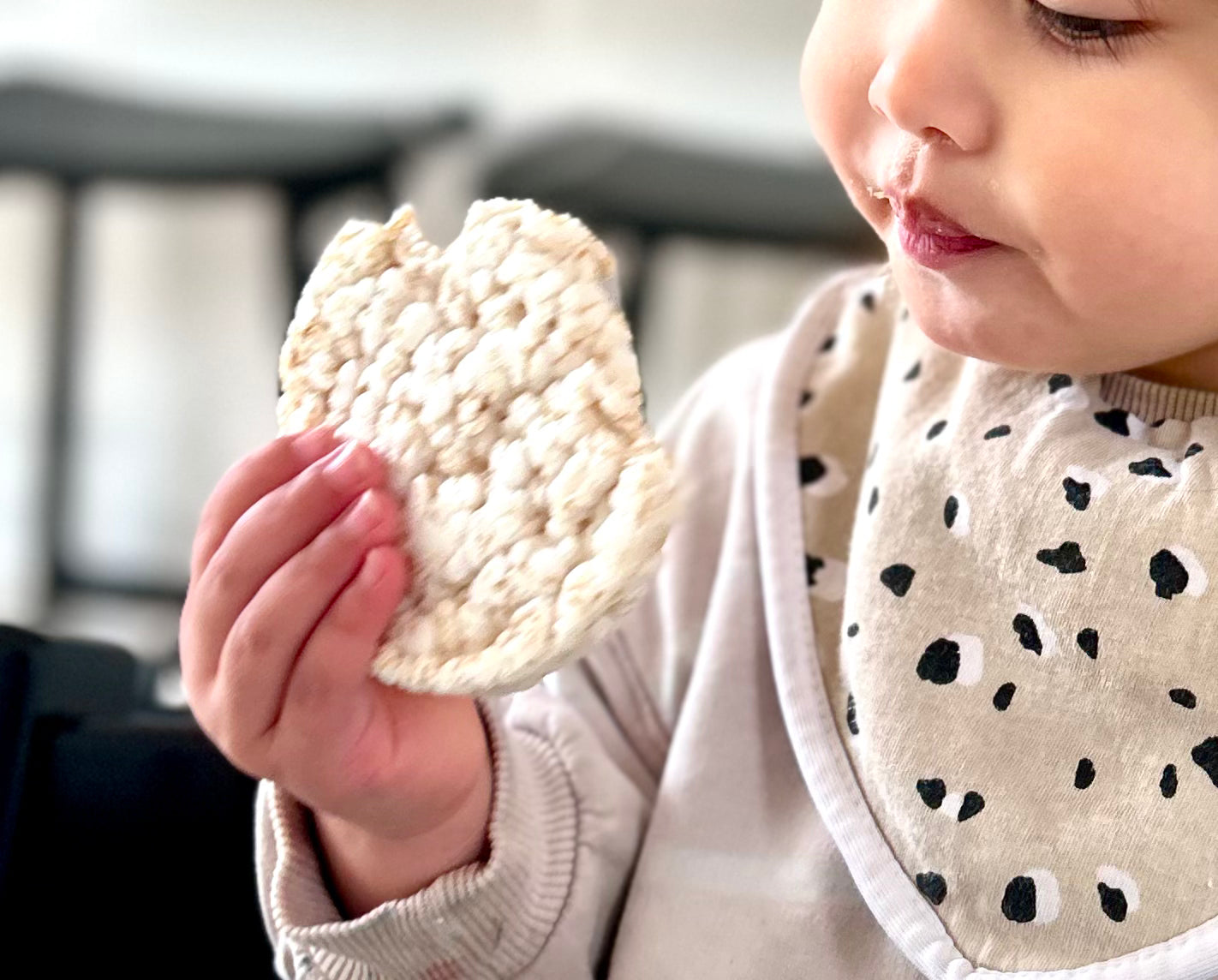 Child holding a round, white rice cake and other healthy snack